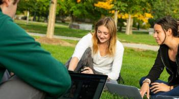 Students sitting on the grass with laptops
