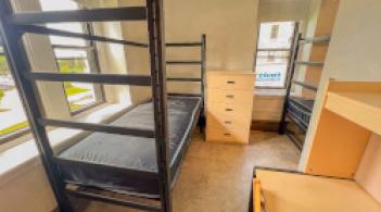A residence hall room with two beds, two desks, two dressers, two wardrobes, and a wall divider.