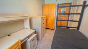 Residence hall room with one bed, one desk. one dresser, and one wardrobe.
