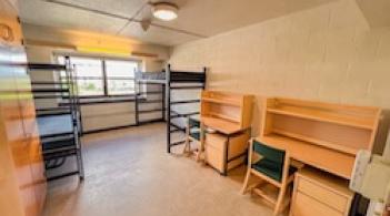 A room with two beds, two built-in closets, and two desks.