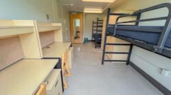 A room with two beds, two armoires, and two desks.
