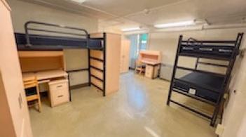 A room with three beds, three armoires, and three desks.