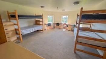 A room with four beds, four dressers/closets, and four desks.