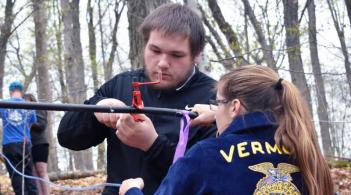 two students working on maple sap tubing outdoors