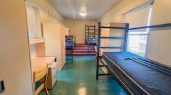 A room with three beds, three desks, and three closets.