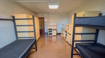 A room with three beds, three dressers, and three desks.