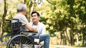 Person kneeling and talking to someone in a wheelchair