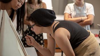 A gathering of art students intently viewing a painting