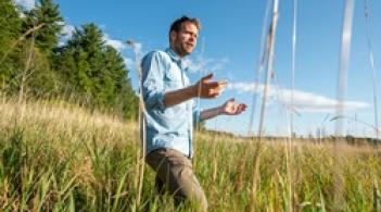 Faculty member Eric Roy standing in a swamp with his arms out gesturing
