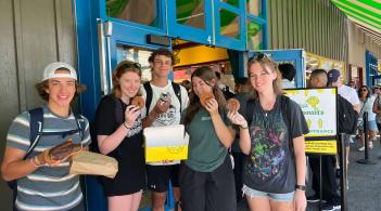 Five students smiling and holding donuts in their hands