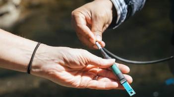 two people's hands hold a piece of scientific equipment