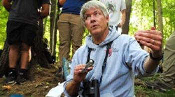 Professor Allan Strong holding a bird and explaining something to a group of students