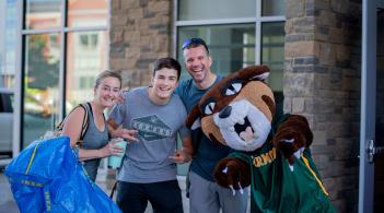 A family on move-in day stands with the Catamount mascot