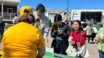 outdoor gathering with people talking at tables and a smoothie truck in the background