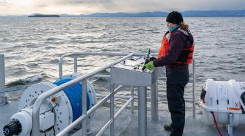 A researcher standing on a boat on the water
