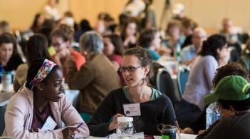 people at a conference, seated at round tables, talking