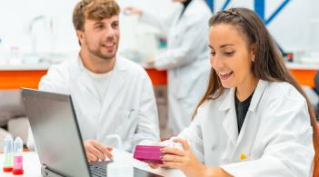 Two people in white lab coats working together in a lab