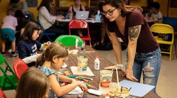 A woman helping children's in painting at a table