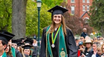 a woman in cap and gown amidst graduation crowd