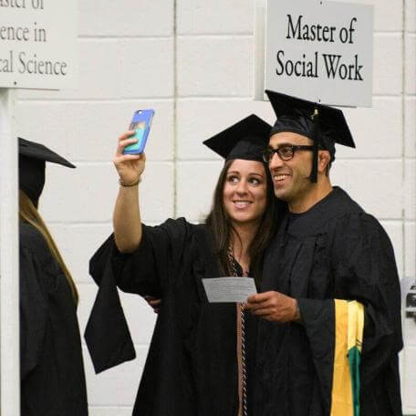 UVM graduates take a smiling selfie