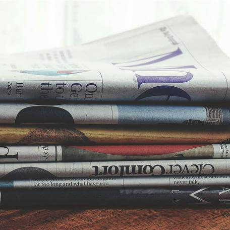 a stack of newspapers on a wooden table