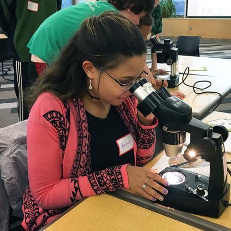 teenager looking into a microscope