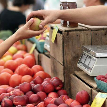 a customer handing a piece of fruit to a shopkeeper