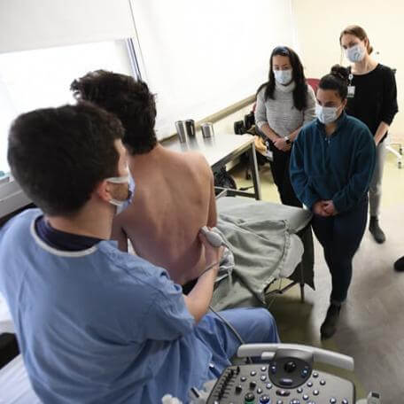 person conduct ultrasound while students observe