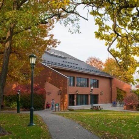 Link, A brick building with large windows. There are trees and green grass and a path in the foreground.