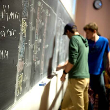 Two students working on an equation at the blackboard