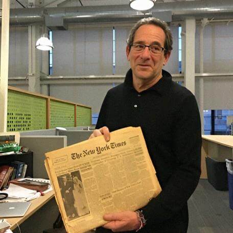 A person standing while holding a newspaper 