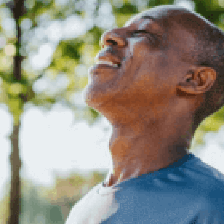 man with eyes closed smiling while looking up