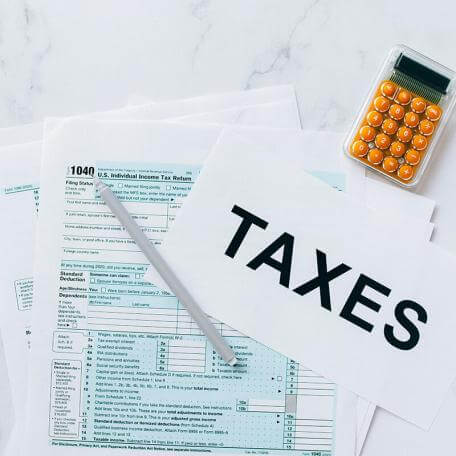 tax forms pencil calculator and sign that reads taxes