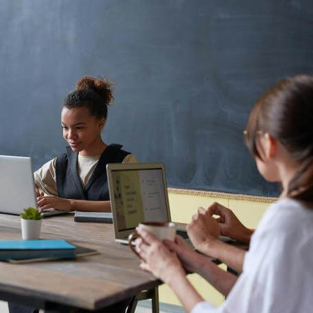 two students in a classroom with laptops