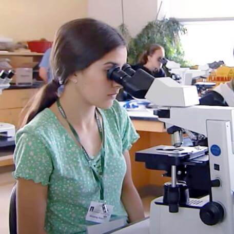 teenager looking into a microscope