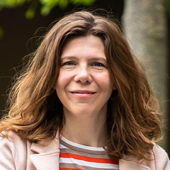a person in a tan jacket with a tree in the background