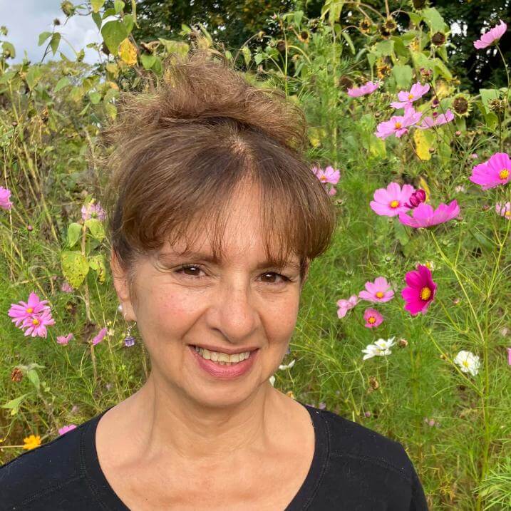 Elena, wearing black shirt and hair up smiling in front of field of pink cosmos