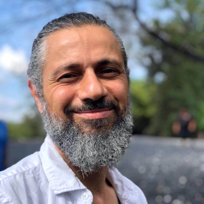 headshot photo of Mohamad, smiling with blurred background of trees and blue sky