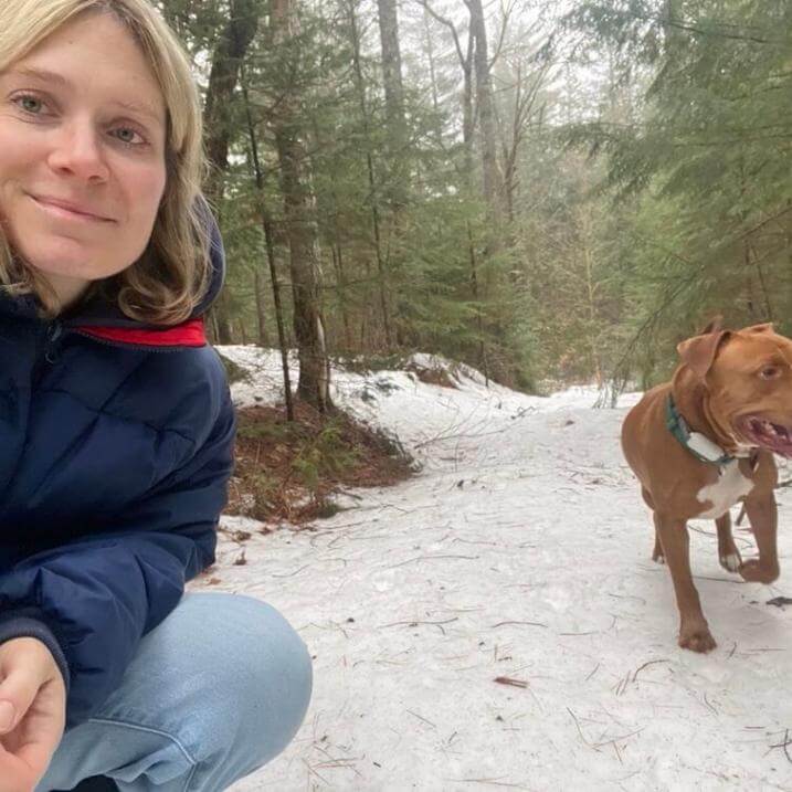 Dru kneeling in a snowy forest with her dog