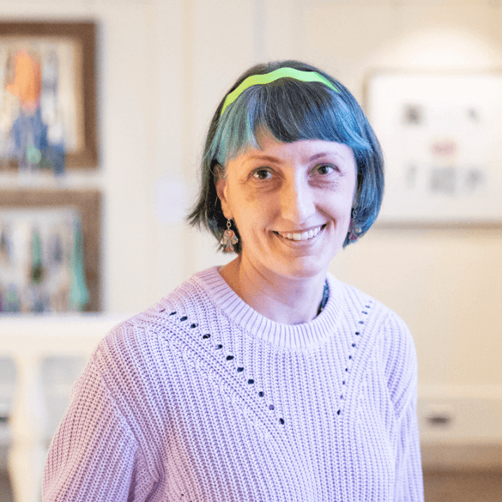 Portrait of curator Kristan M. Hanson, she wears a light purple sweater and is smiling.