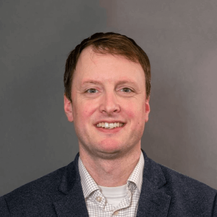 Researcher smiling posed against a grey background