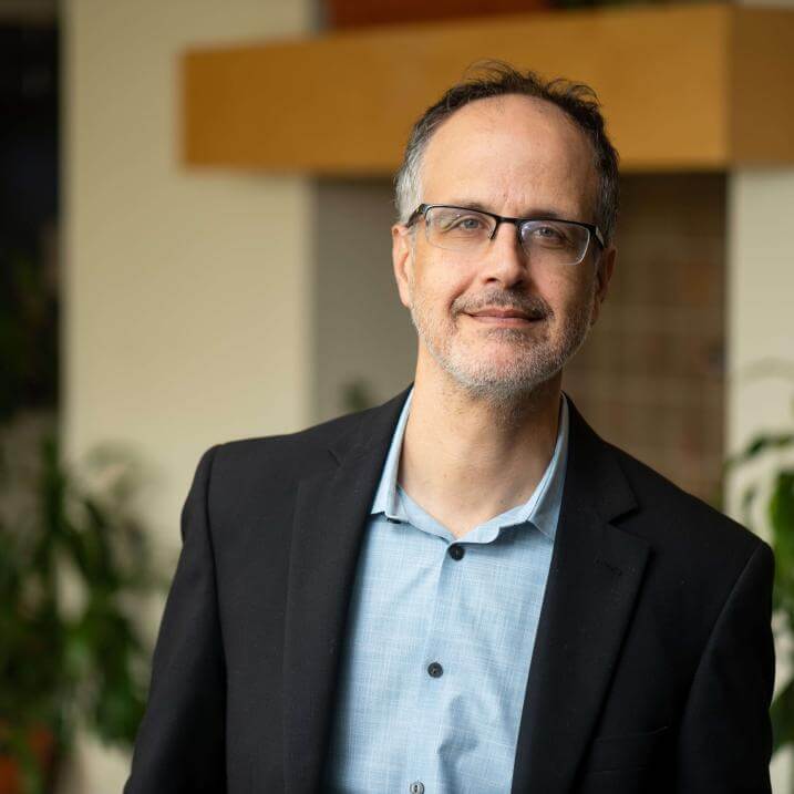 A person wearing black blazer and glasses