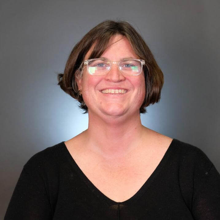 A person with brown hair and glasses wearing a black shirt