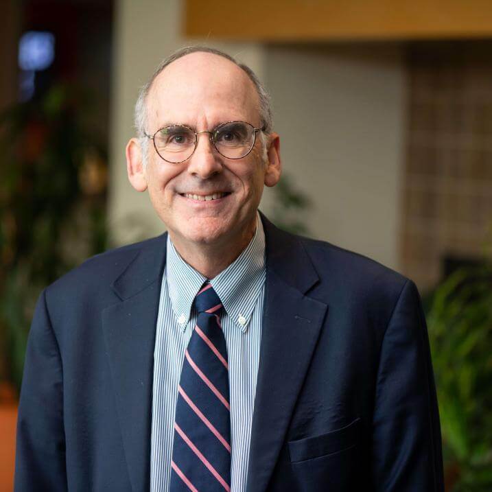 A person wearing a blazer and a striped tie