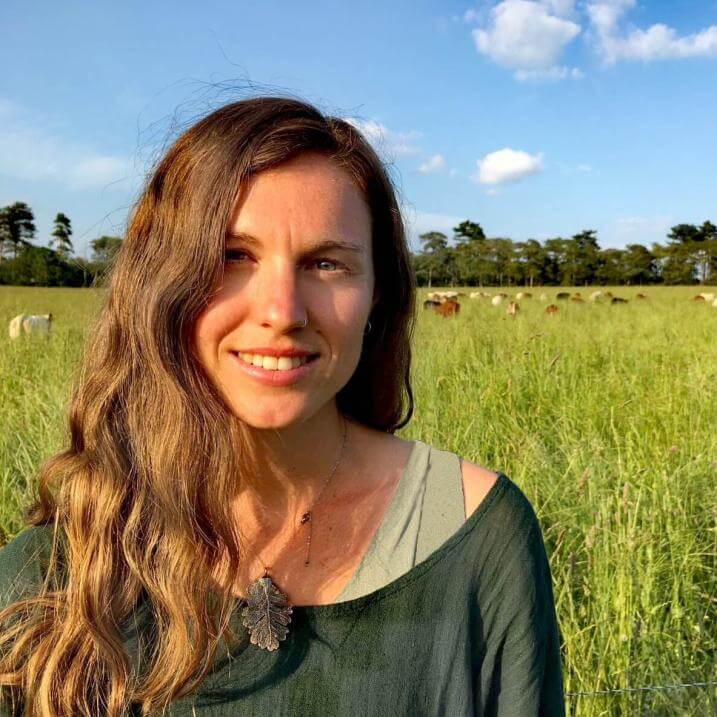Bryony Sands in a field with animals grazing behind her