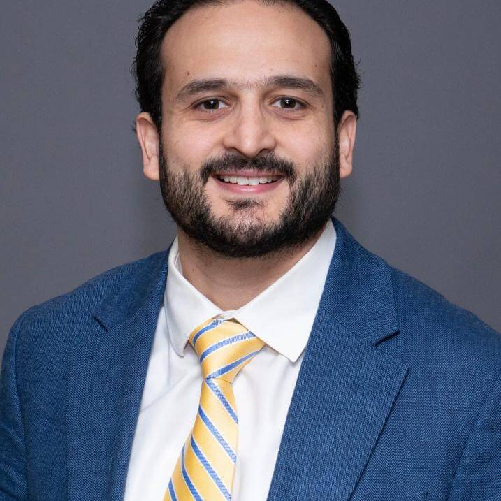 A person in a blue blazer and a yellow striped tie
