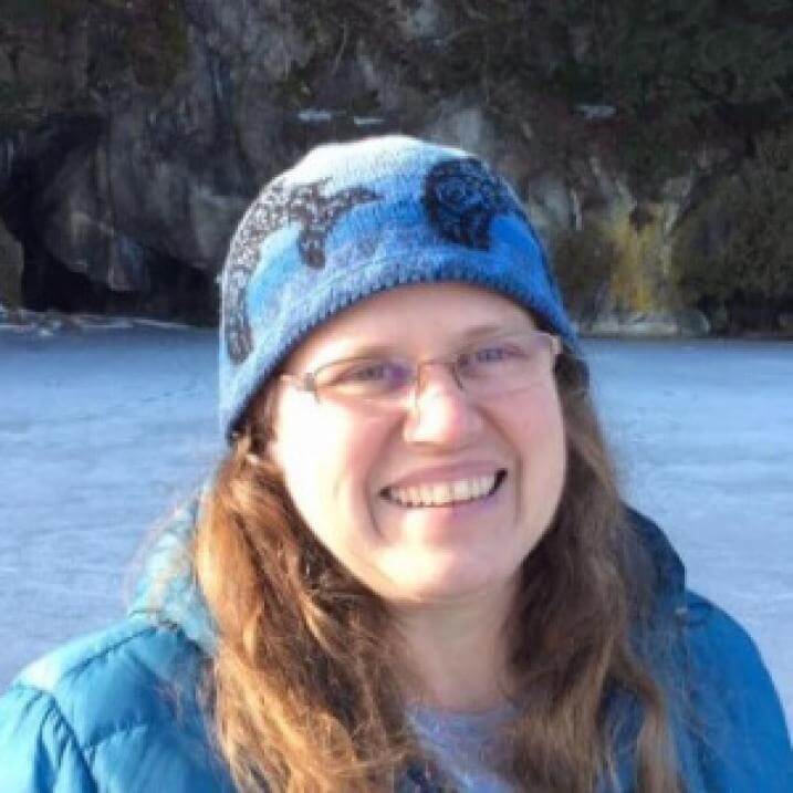 Alicia smiling in a winter hat on a frozen pond