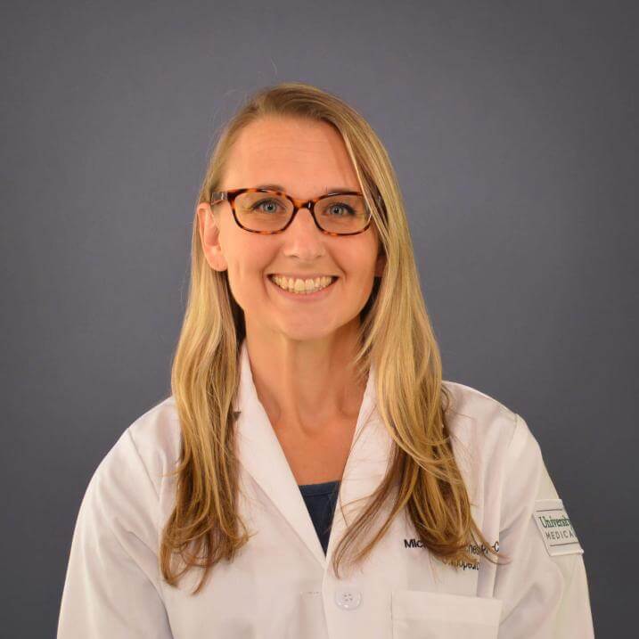 A person wearing a white coat and glasses