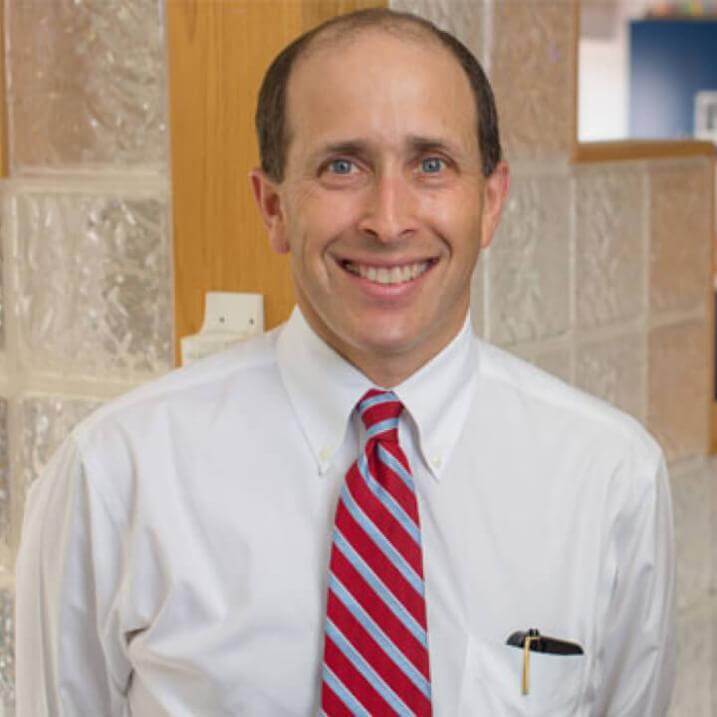 A person wearing a white shirt and a red striped tie