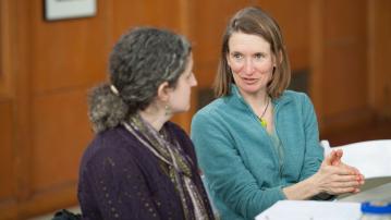 Susan Munkres speaks with a faculty member inside of a university building.